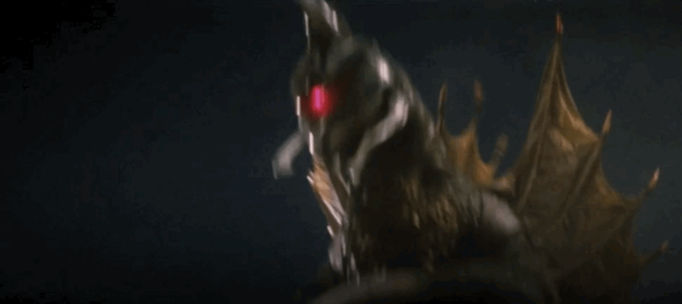 Gigan leaps at Godzilla, slicing him with his buzzsaw, and a fountain of blood spews out.