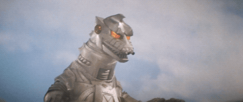 Mechagodzilla shoots King Caesar with rainbow beam, which is reflected before King Caesar charges Mechagodzilla to the ground