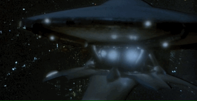 A flying saucer approaches Tokyo, lights flashing rapidly.