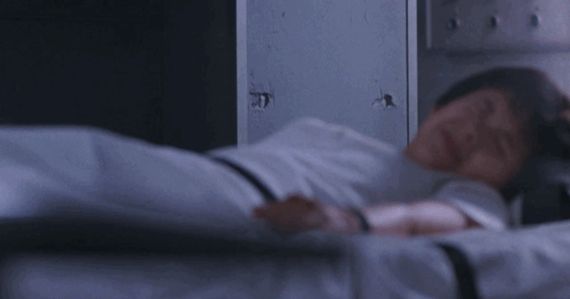 A mobster flips the bed with Miki strapped to and uses it as cover in a shootout