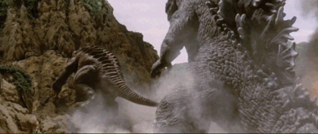 A four legged monster with large ears tries to climb up a hill while Godzilla waits crouched, charging his spines. After a deep breath, atomic fury is unleashed on the creature
