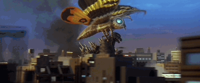 Mothra drags Godzilla across the city, slamming him into a bridge