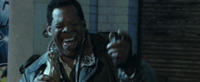 A black pimp and a white cop draw guns on each other before their hats fly off comedically